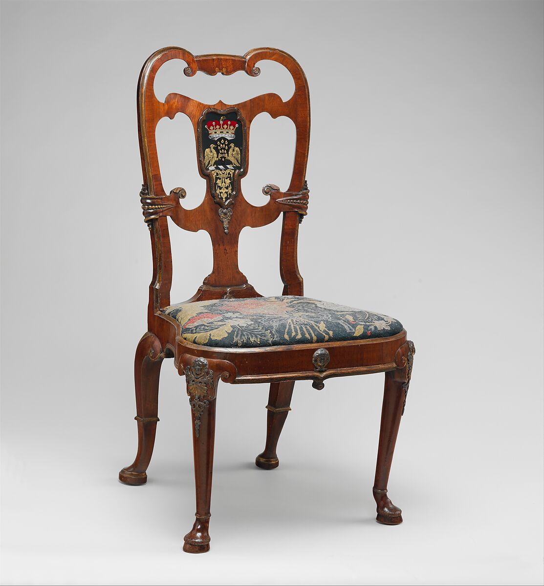 Pair of side chairs, Attributed to Thomas How (British, active 1710–33), Walnut and walnut veneer, parcel-gilt, the seat rails of beech; gilded lead mounts on the knees and front rail; verre églomisé panel mounted on the splat; covered in contemporary tent stitch embroidery on canvas needlework not original to the chair, British