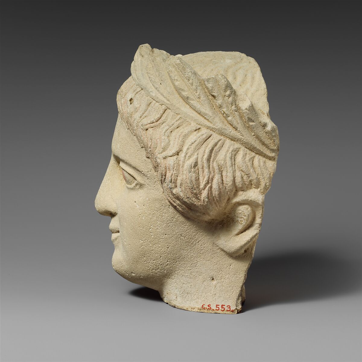 Limestone head of a beardless male votary with a wreath of leaves, Limestone, Cypriot