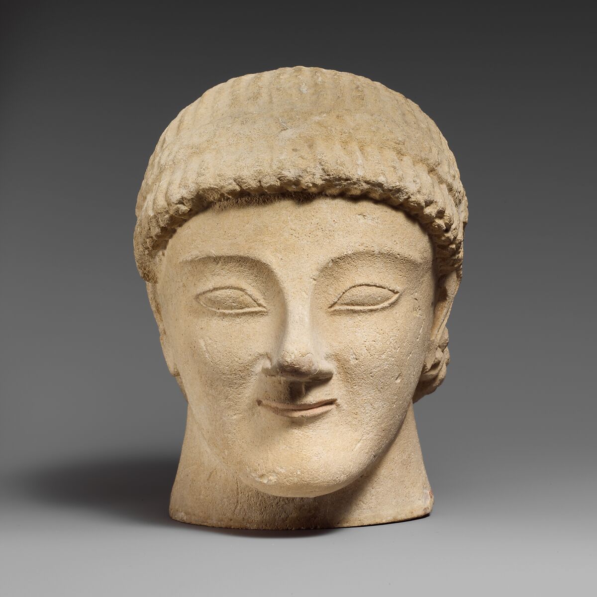 Limestone head of a beardless male votary with a wreath of rosettes, Limestone, Cypriot 