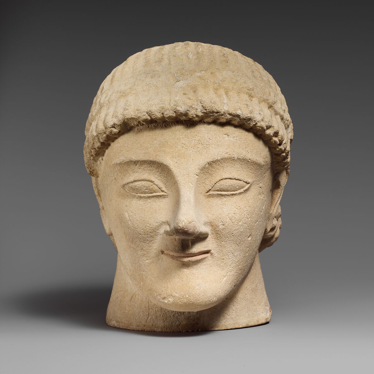 Limestone head of a beardless male votary with a wreath of rosettes, Limestone, Cypriot 