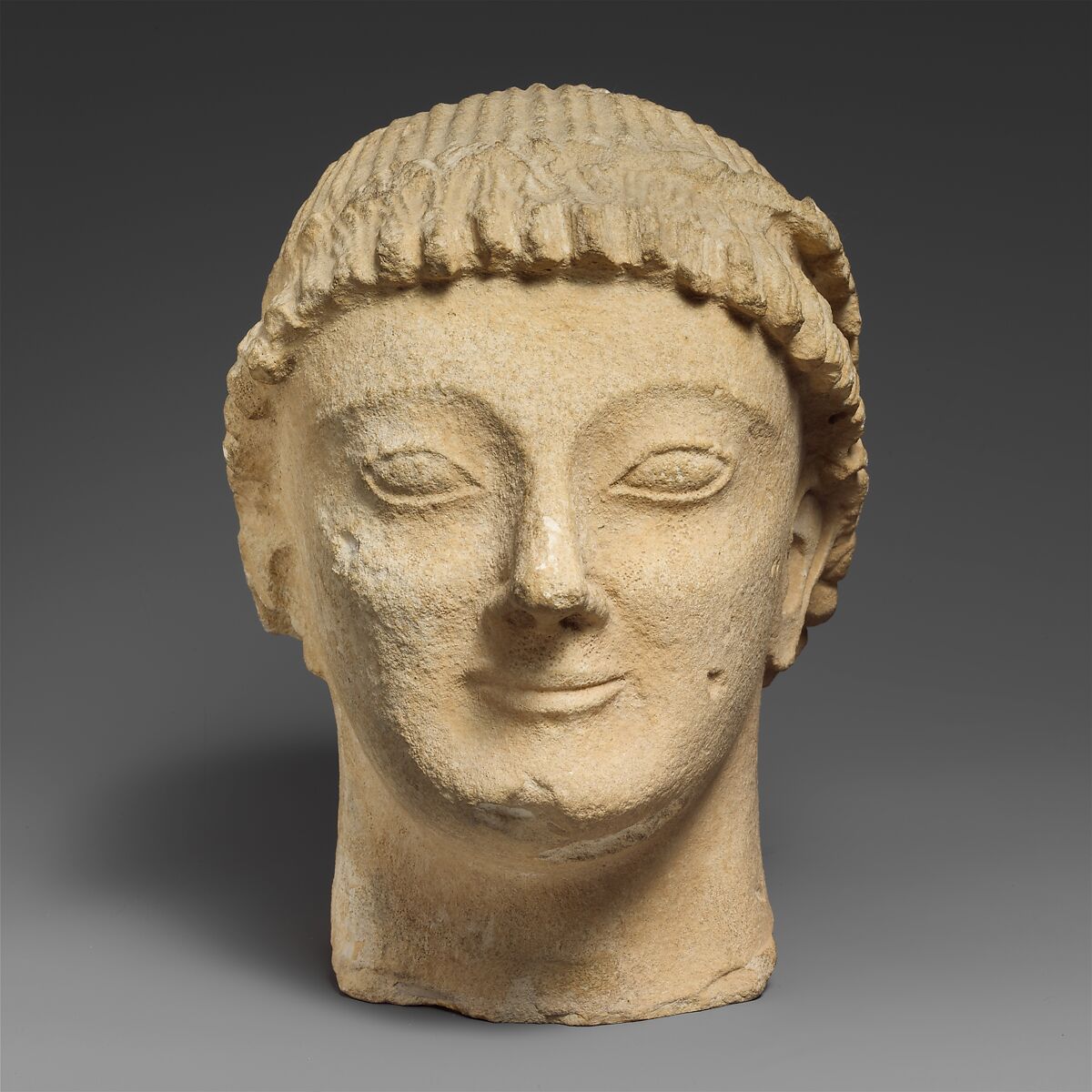 Limestone head of a beardless male votary with a wreath of rosettes, Limestone, Cypriot 