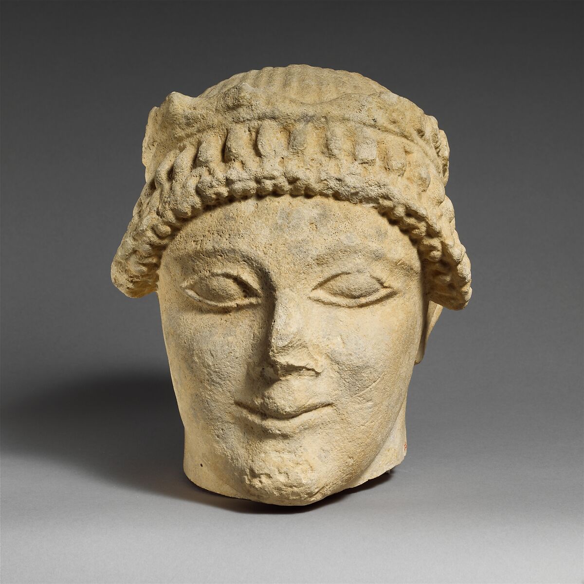 Limestone head of a beardless male votary with a wreath of leaves, Limestone, Cypriot 