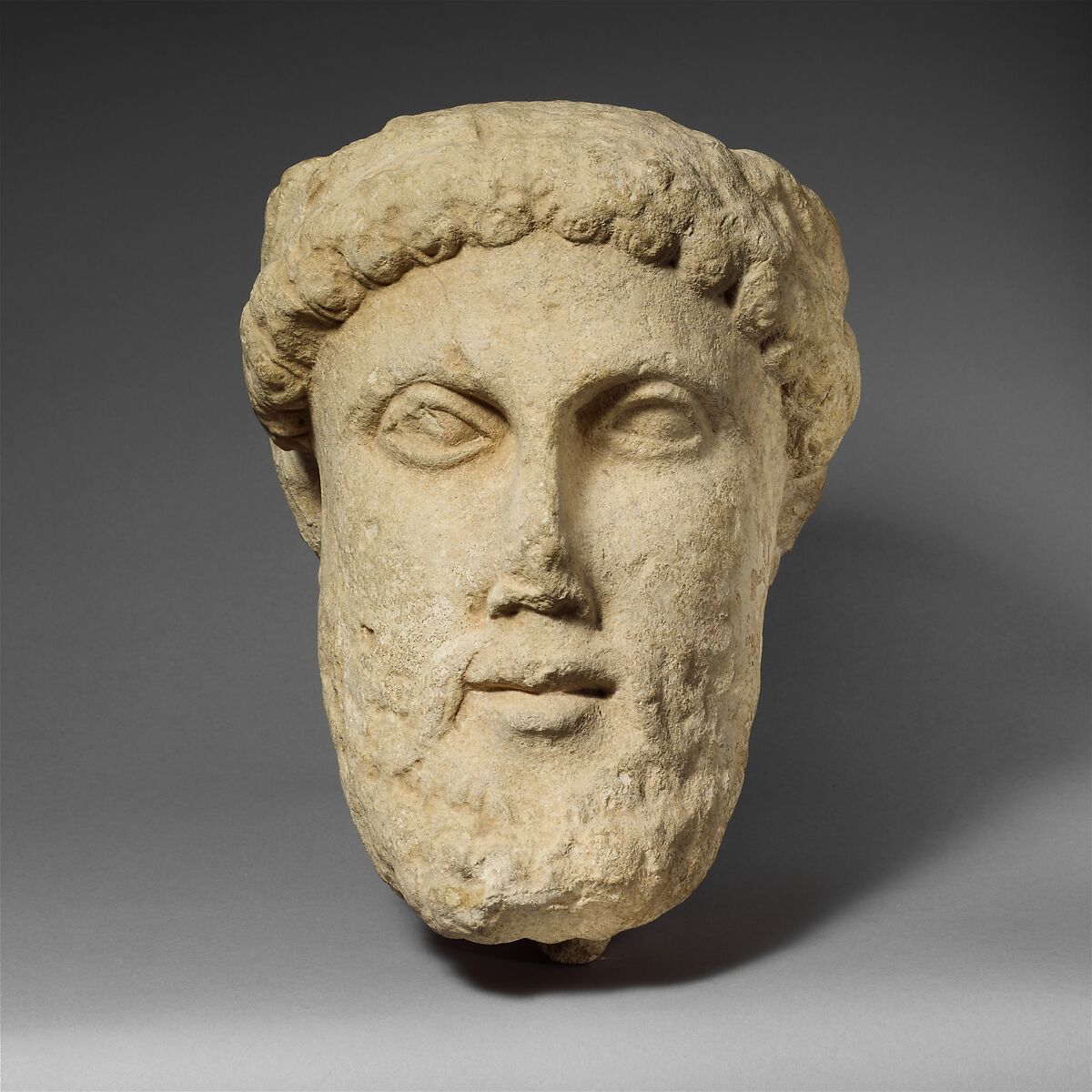 Limestone head of a bearded male with a wreath of leaves, Limestone, Cypriot 