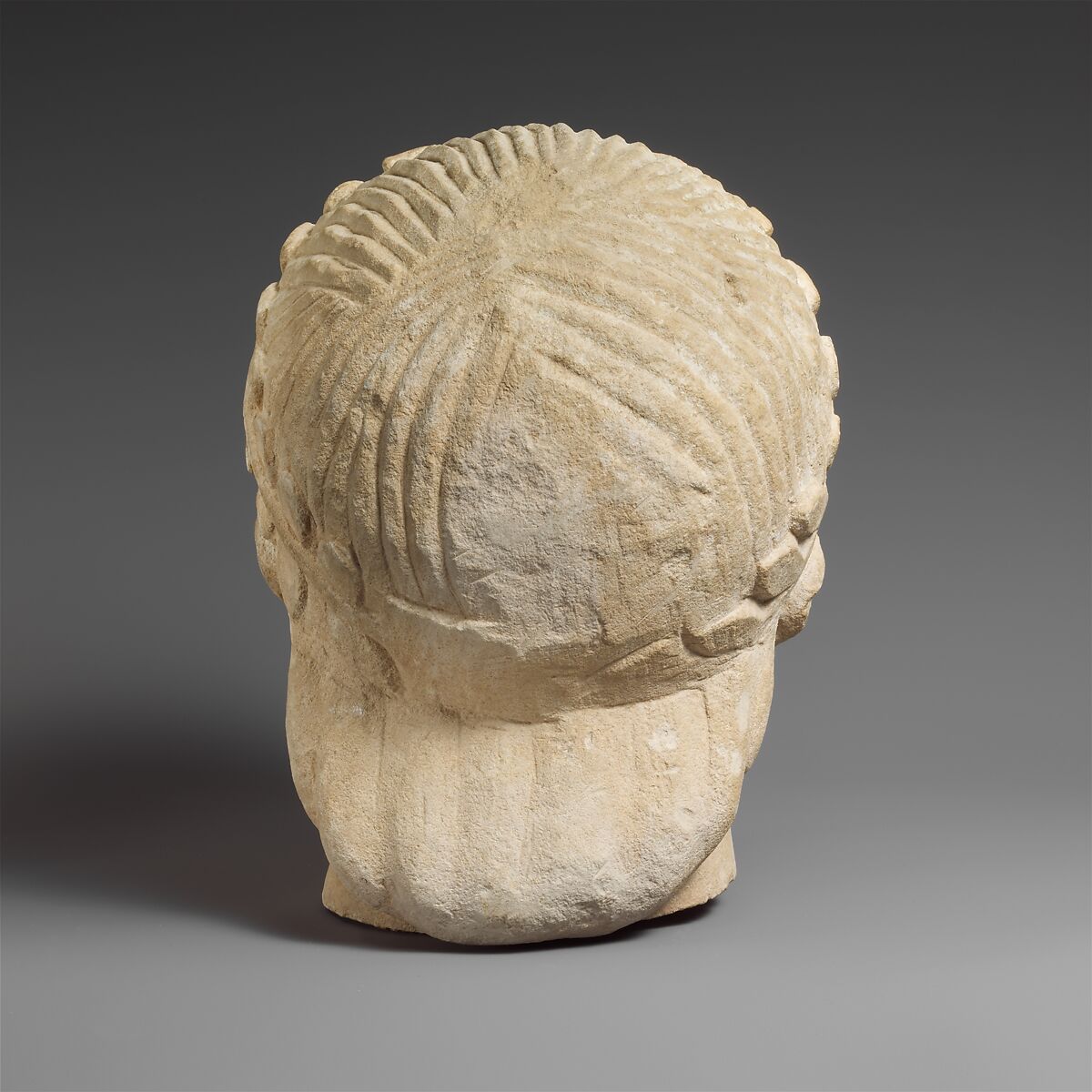 Limestone head of a beardless male votary with a wreath of leaves, Limestone, Cypriot