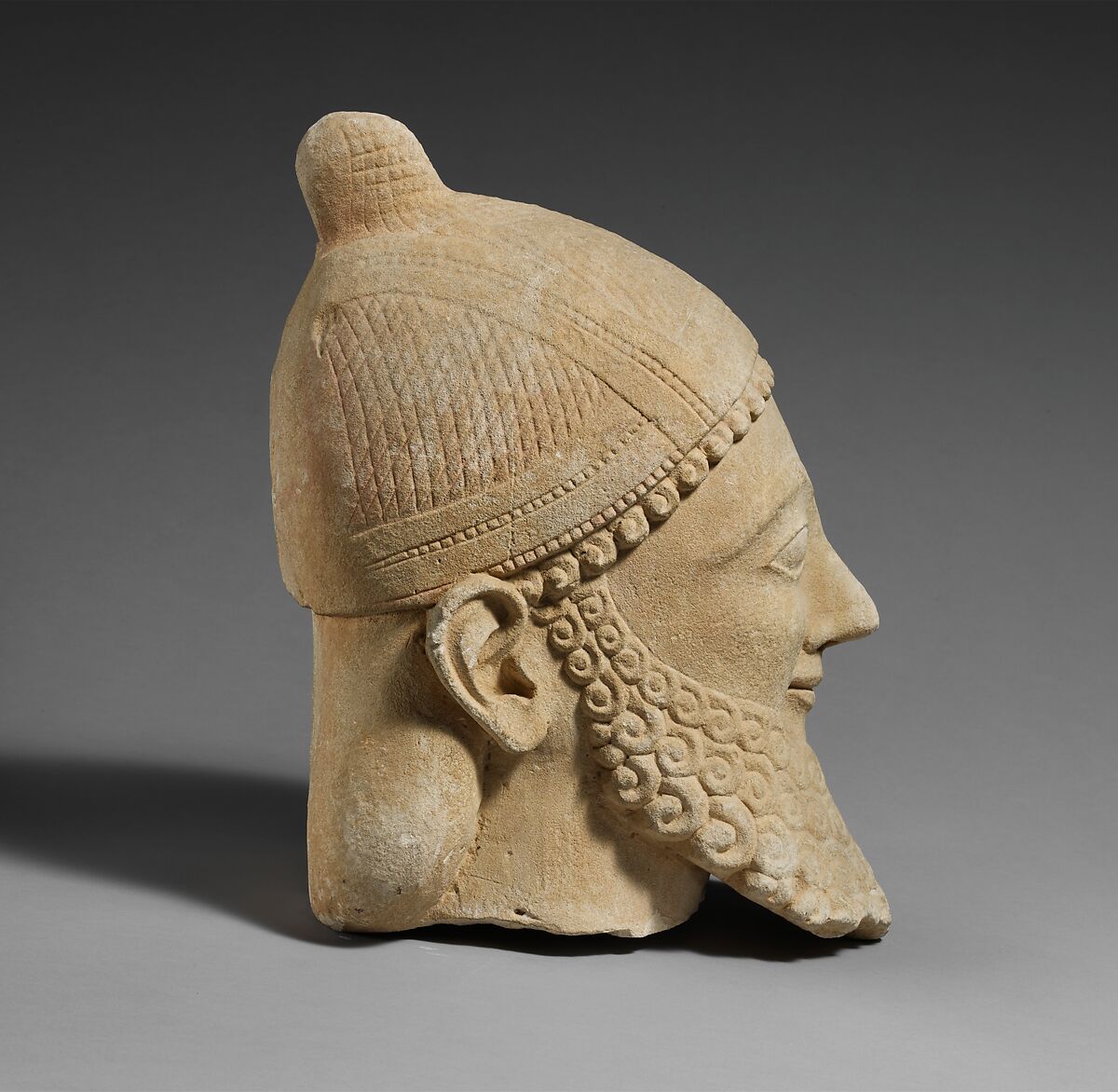 Limestone head of a bearded male wearing a conical helmet, Limestone, Cypriot