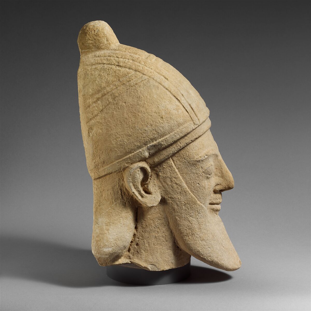 Limestone head of a bearded male wearing a conical helmet, Limestone, Cypriot