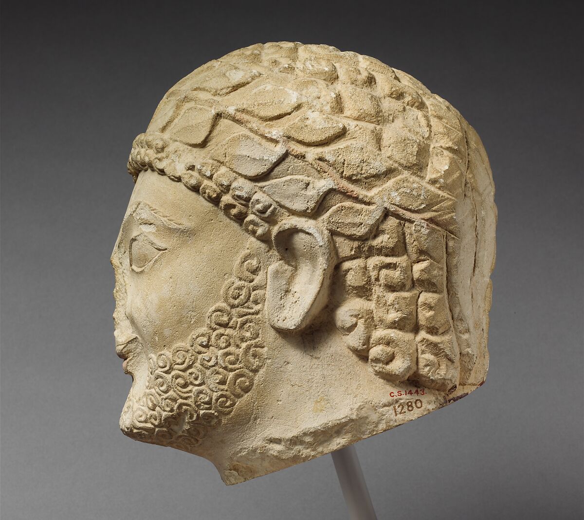 Limestone head of a bearded male with a wreath of leaves, Limestone, Cypriot