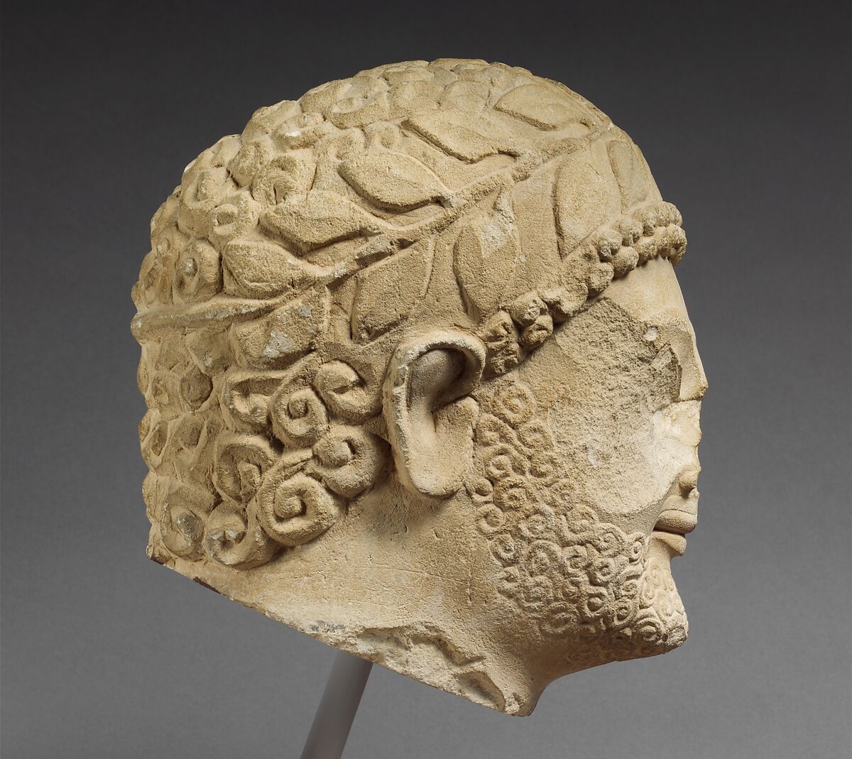 Limestone head of a bearded male with a wreath of leaves, Limestone, Cypriot