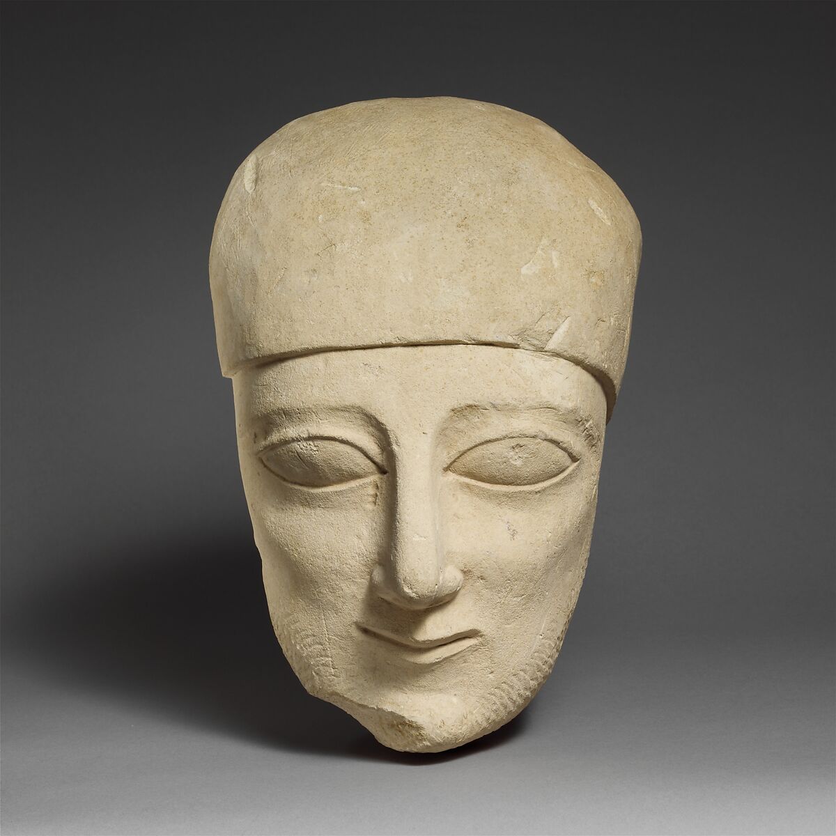 Fragment of a limestone head of a bearded male with a plain headdress, Limestone, Cypriot 