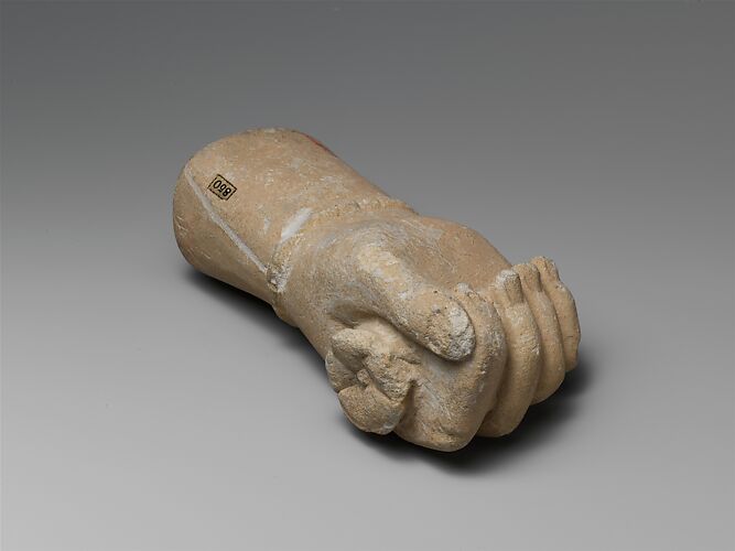 Limestone statue fragment of a right hand with a bracelet, holding a flower