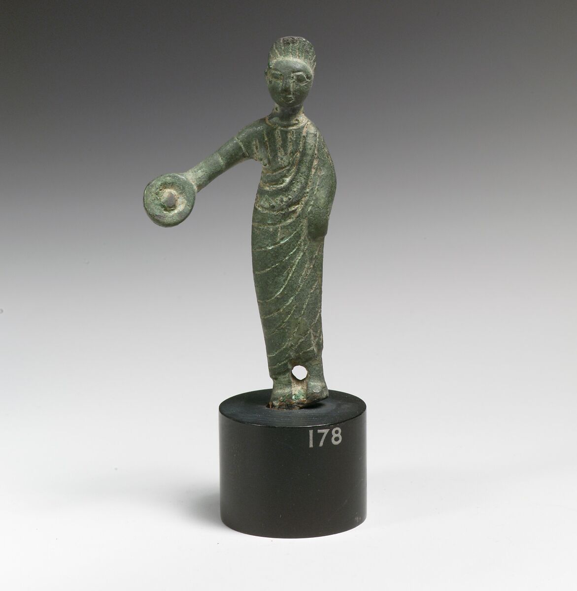 Statuette of a woman holding a phiale (libation vessel), Bronze 