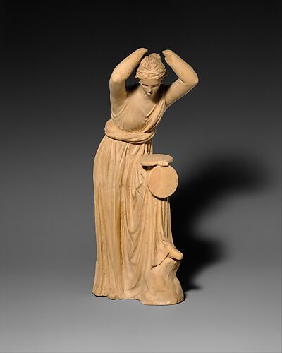 Terracotta statuette of a woman looking into a box mirror