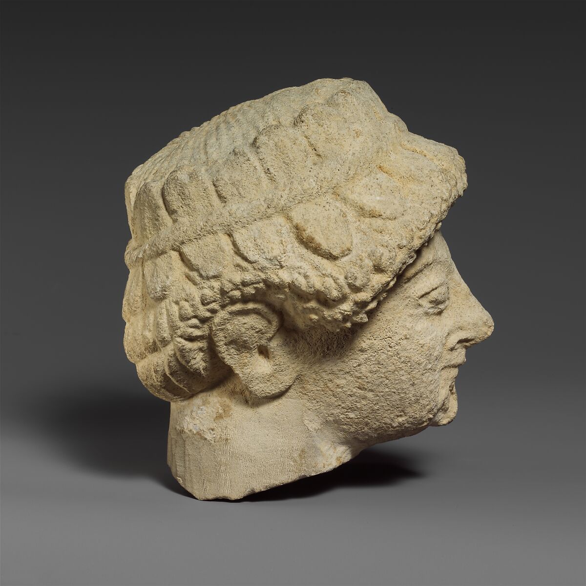Limestone head with of a beardless male with a wreath of leaves, Limestone, Cypriot