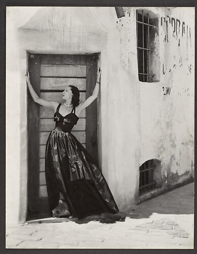 [Woman in Long Dress, Standing in Doorway of Stuccoed Building]