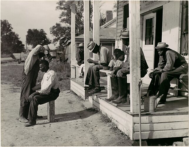 [Haircutting in Front of General Store and Post Office on Marcella Plantation, Mileston, Mississippi]