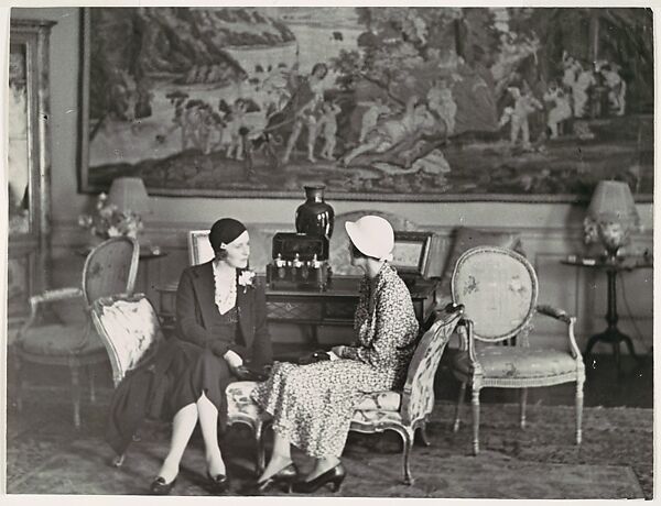 [Two Women, Seated and in Conversation, in Interior Setting]