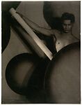 [Upper Torso of Young Male Nude, Holding Long White Rod and Posed behind Large, Dark, Circular Forms]