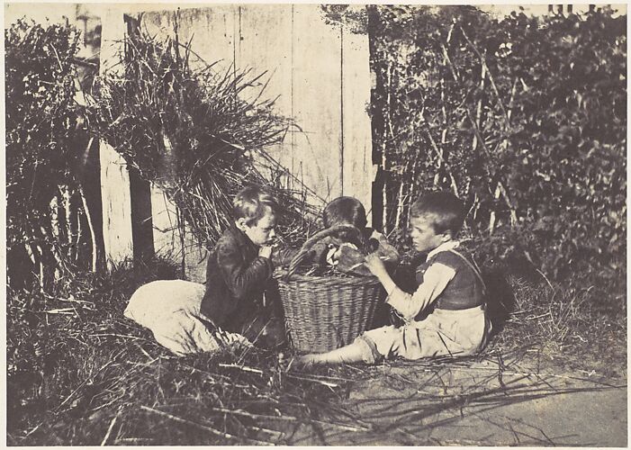Trois jeunes enfants assis autour d'un panier