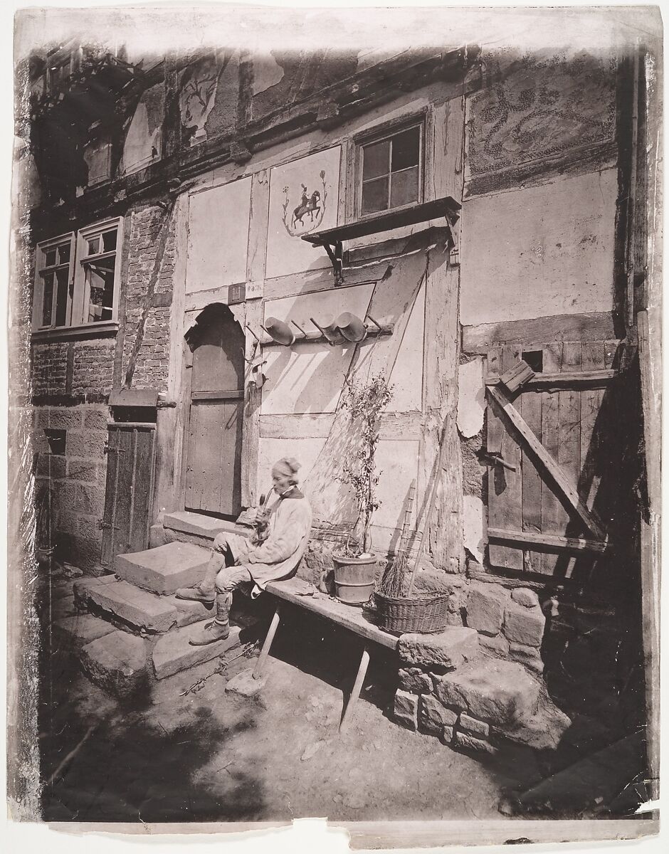 [Man Smoking Pipe Outside His Home on Village Street], Unknown (German), Collotype 