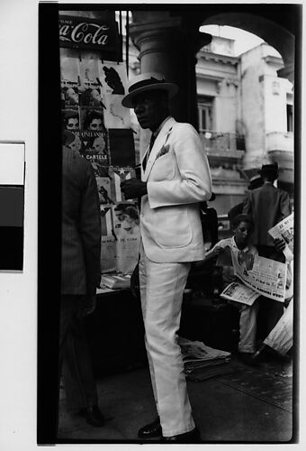 [Man in White Suit and Straw Hat in Front of Newspaper Kiosk, Havana]