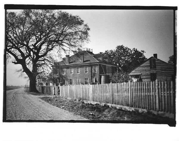 [Side View of Brick House Behind Picket Fence, From Automobile, Louisiana]
