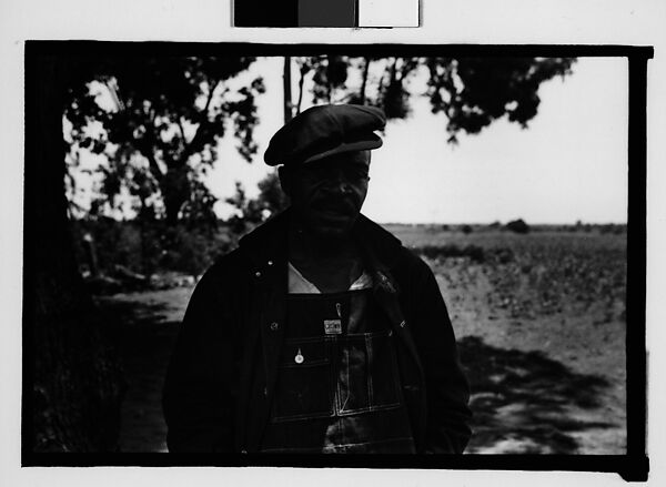 [Man Wearing Cap and Overalls Standing Next to Tree, Hale County?, Alabama]