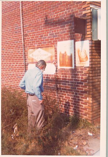 [Walker Evans in Front of Brick Wall with Commercial Signs, Alabama]