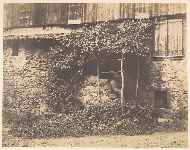 [Rustic Building with Man under Trellis]