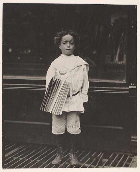 Jo Lehman, a 7 year old newsboy. 824 Third Ave., N.Y. City. He was selling in this Saloon. I asked him about the badge he was wearing.  "Oh! Dat's me bruder's," he said. Location: New York, New York., Lewis Hine (American, 1874–1940), Gelatin silver print 