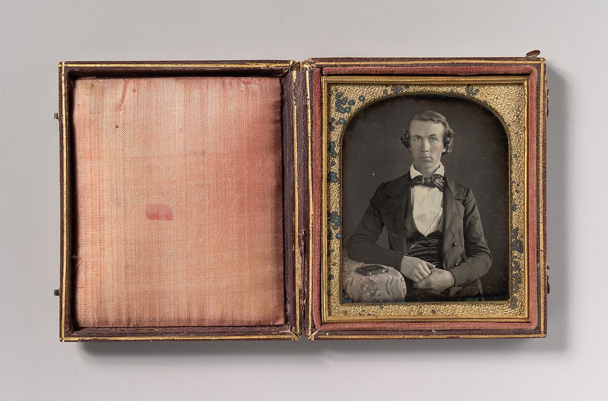 [Seated Young Man Resting Arm on Table Beside Daguerreotype Case], Unknown (American), Daguerreotype with applied color 