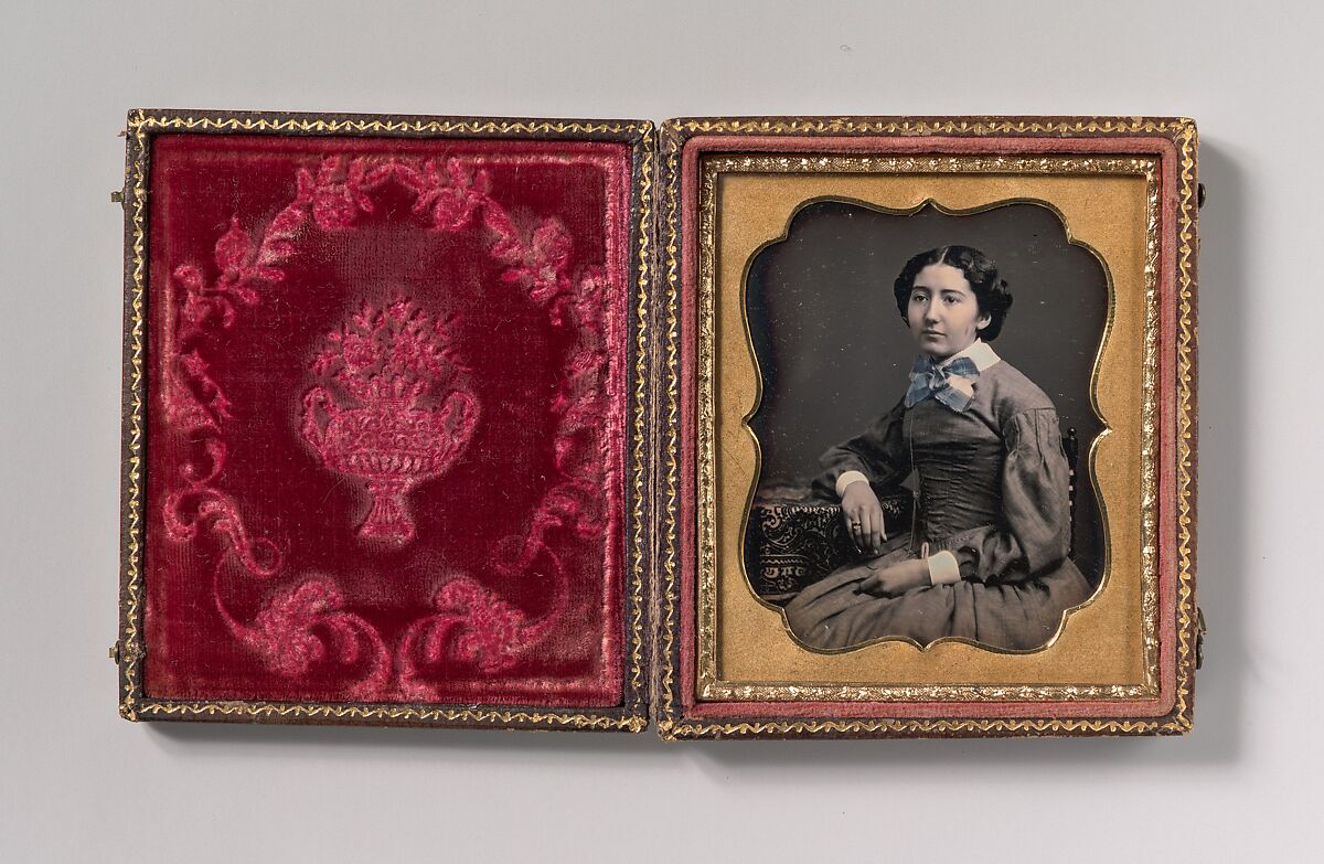 [Seated Young Woman Wearing Collar with Large Bow, Resting Arm on Table], Unknown (American), Daguerreotype with applied color 
