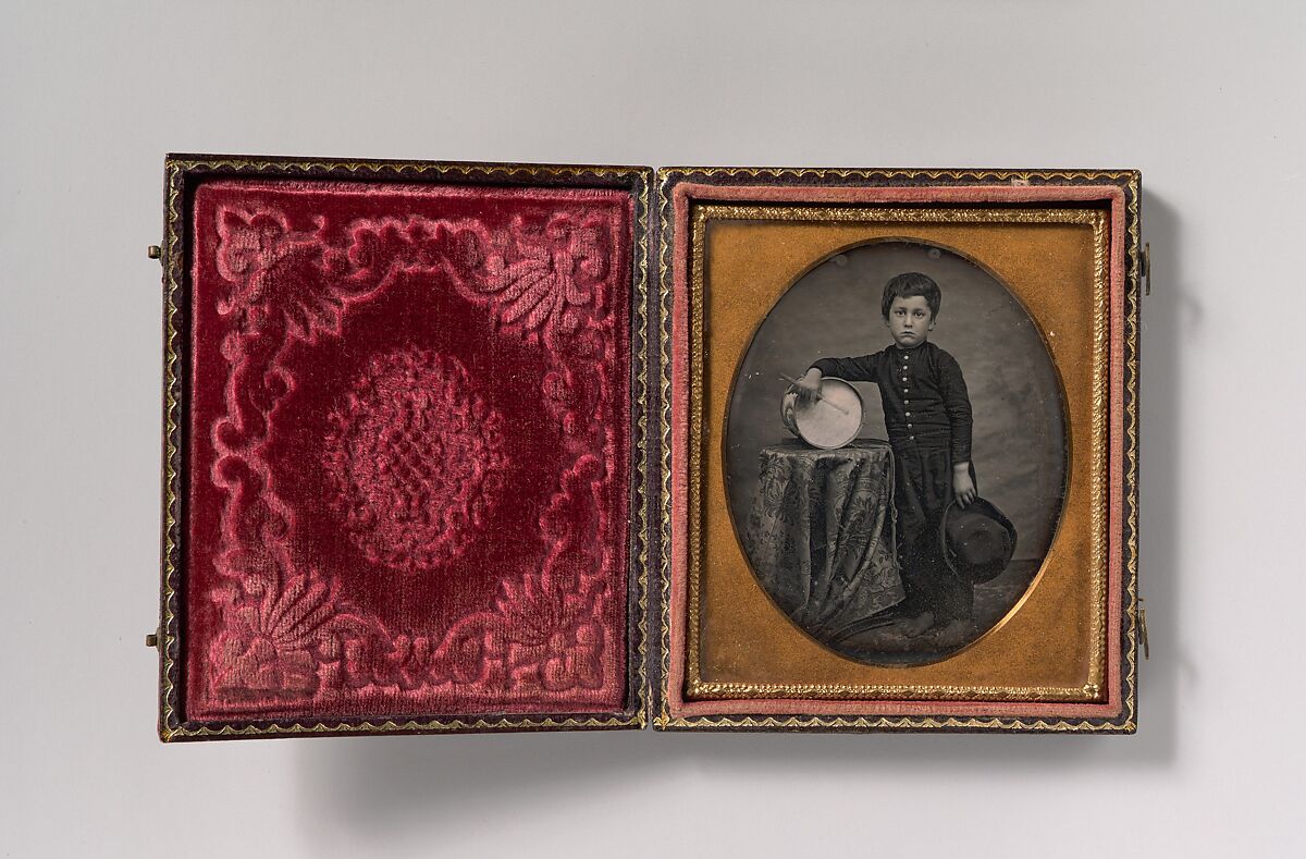 [Barefoot Boy Holding Hat and Drum Stick, Leaning Forearm on Child-sized Drum on Table], Unknown (American), Daguerreotype 