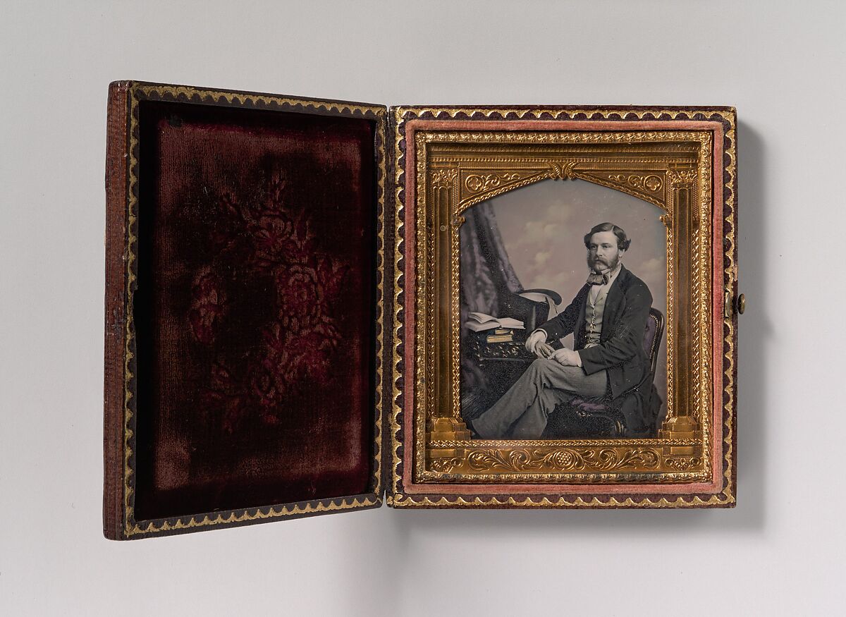 [Man Seated in Front of Cloud Backdrop, Books and Top Hat on Table], Unknown, Daguerreotype with applied color 