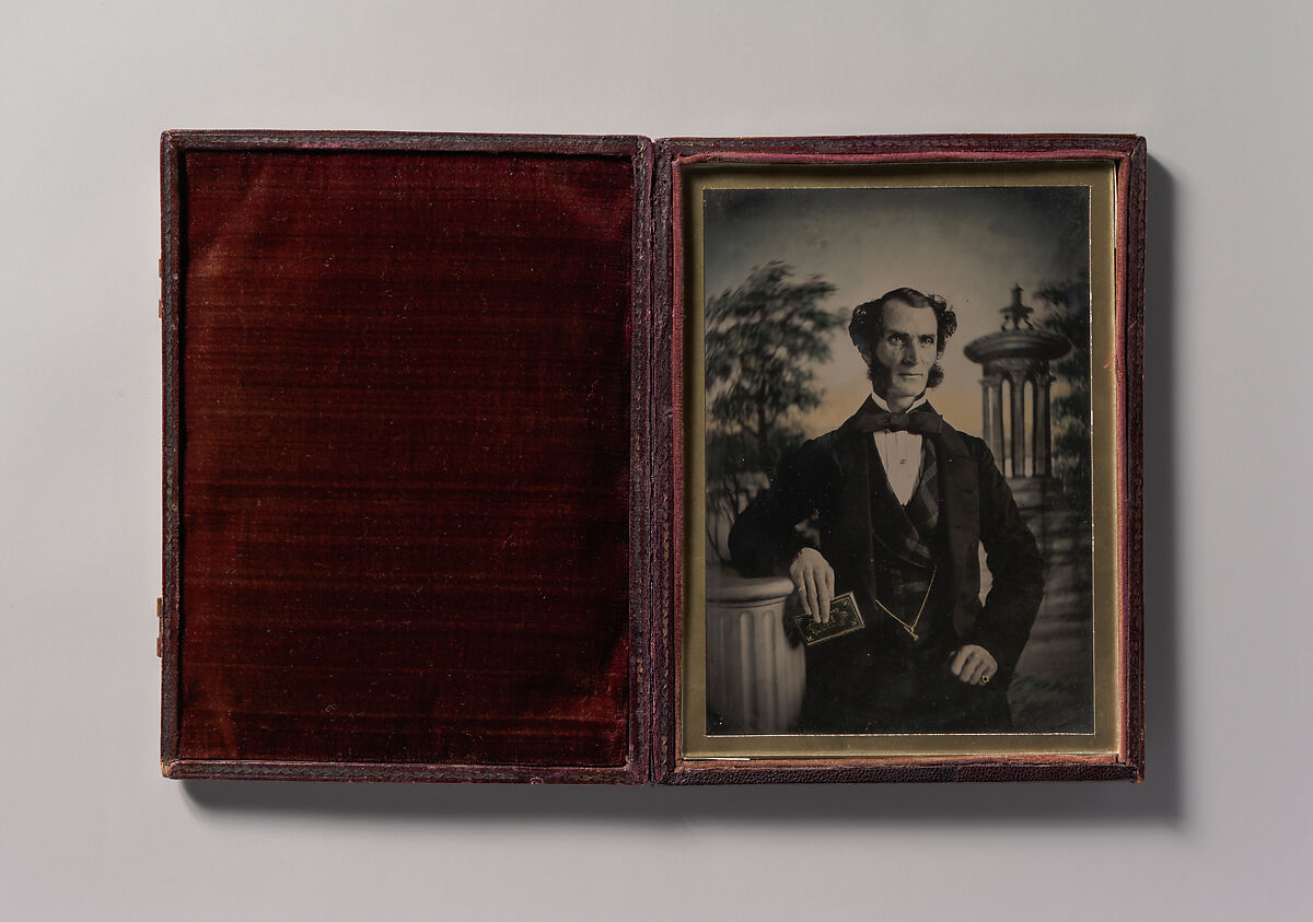 [Man Holding Book, Standing Before a Painted Scenic Backdrop], Unknown (British), Ambrotype with applied color 