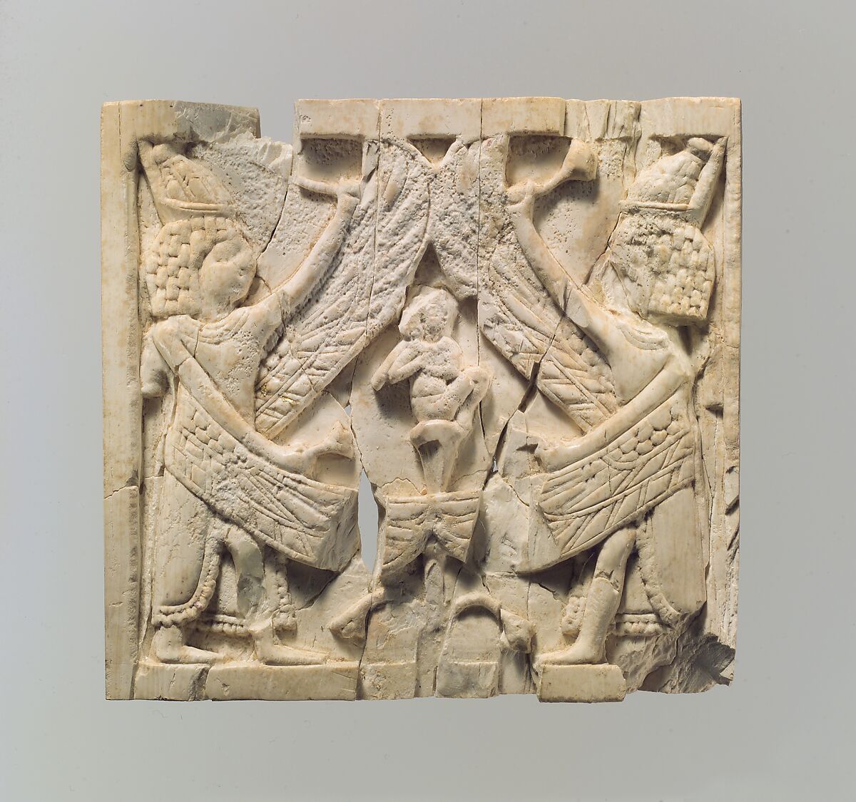 Furniture plaque carved in relief showing two winged, male figures flanking an infant on a lotus flower, Ivory, Assyrian 