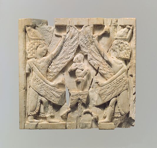 Furniture plaque carved in relief showing two winged, male figures flanking an infant on a lotus flower