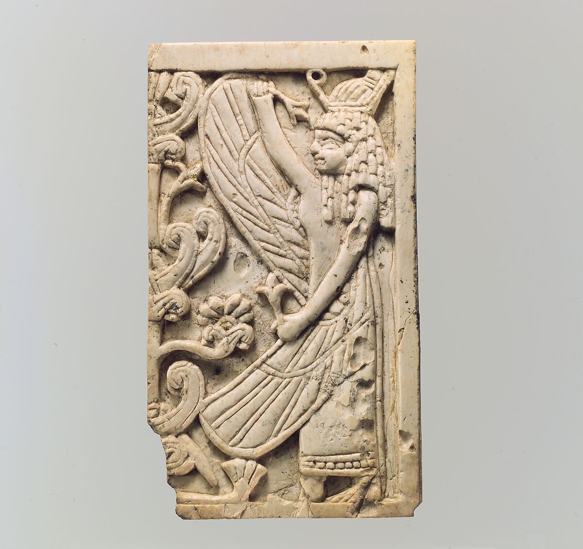 Furniture plaque carved in relief with a winged female figure and a “sacred tree”, Ivory, gold, Assyrian 