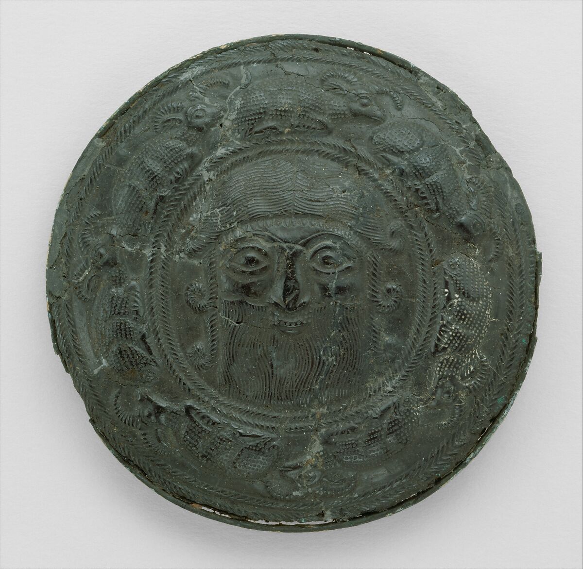 Roundel with head of a "hero" surrounded by caprids, Bitumen, gold and silver foil, Elamite 