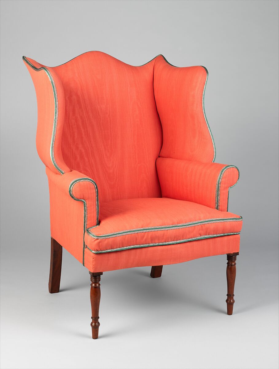 A bright orange easy chair with mahogany legs. 