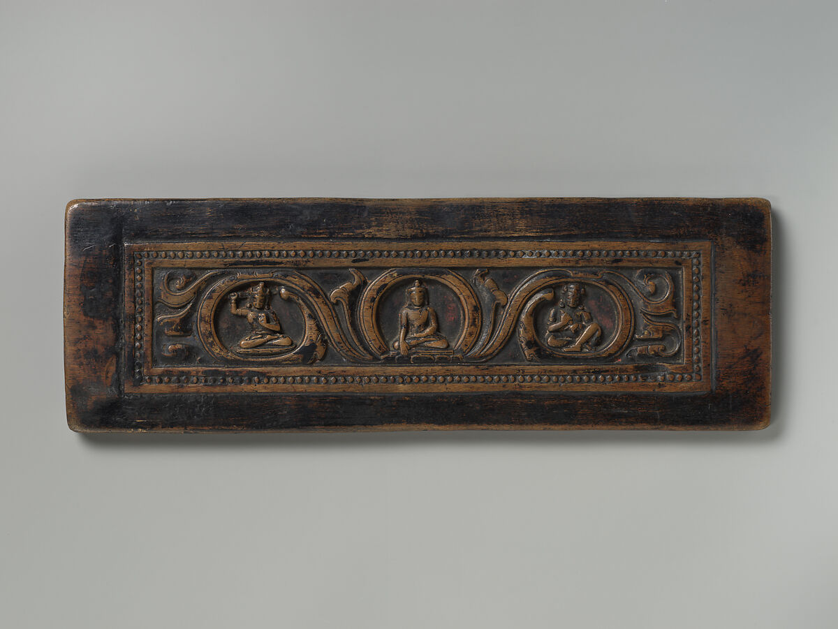 Manuscript Cover with the Buddha Shakyamuni, Attended by Manjushri and Vajrapani, Wood with traces of red paint, Tibet 