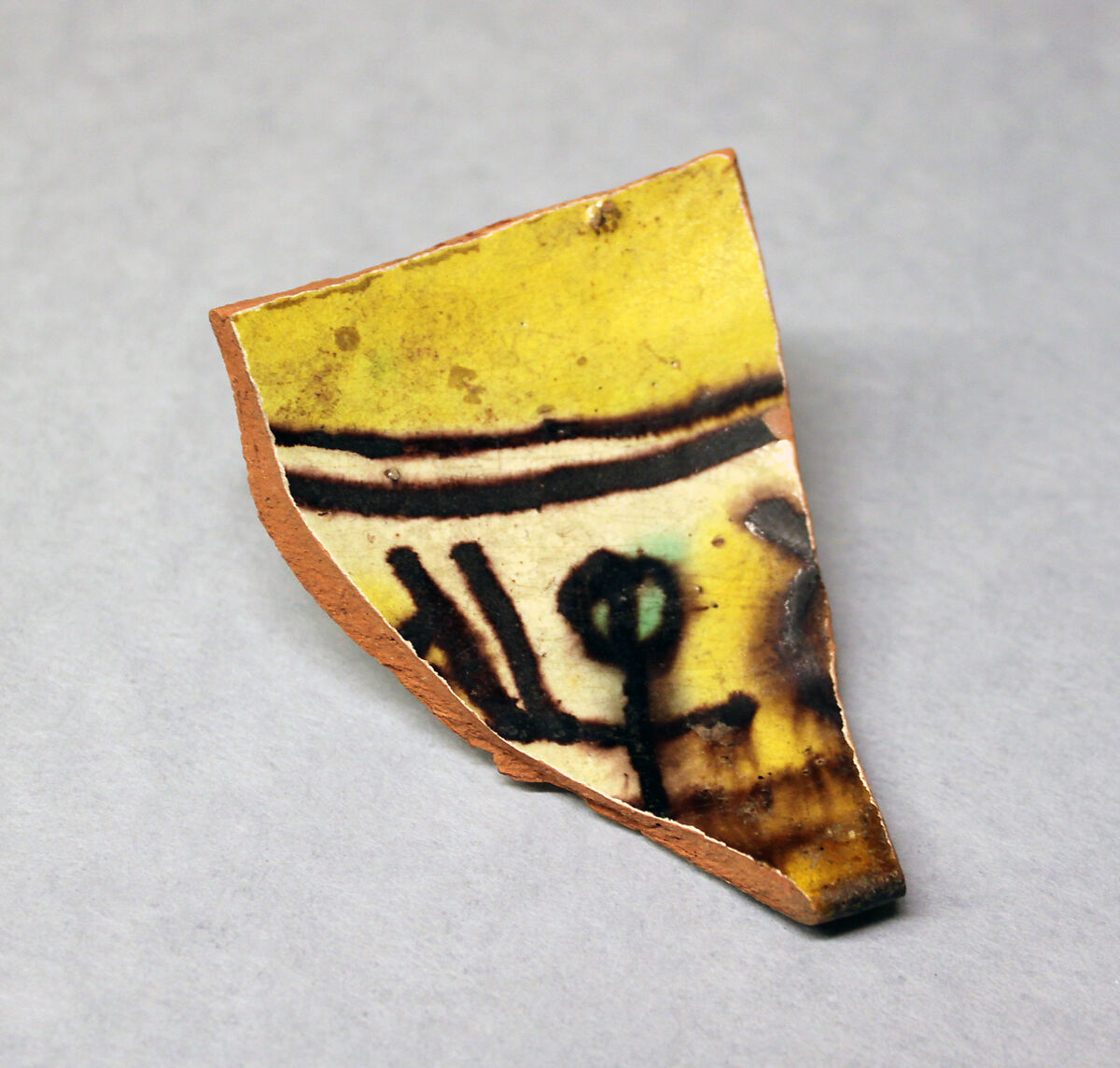 Fragment of a Bowl, Earthenware; red body, white slip, slip decoration in yellow, green and brown-black under glaze 