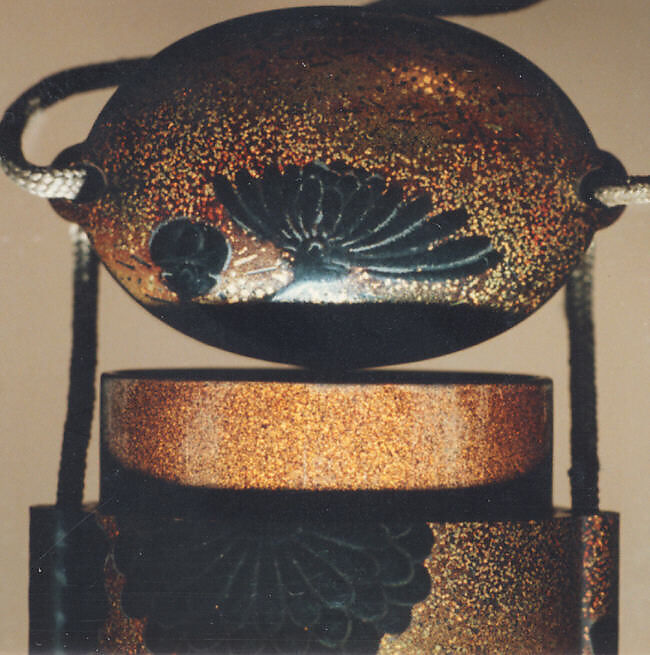 Case (Inrō) with Design of Chrysanthemums, Black and sprinkled gold lacquer; Ojime: tiger-eye bead; Netsuke: cluster of masks carved in ivory, Japan