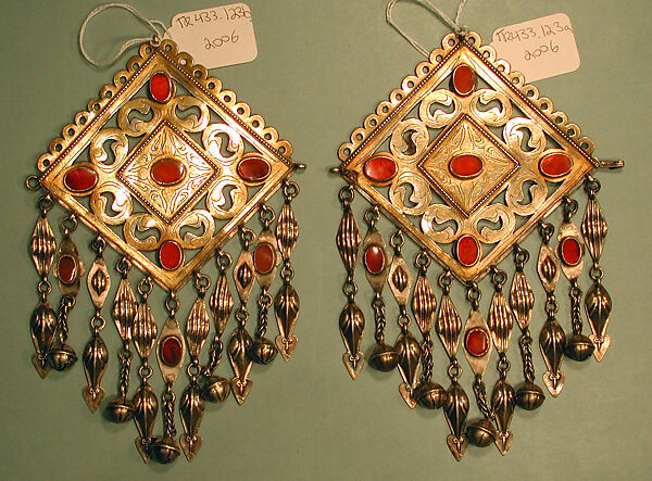 Pair of Pectoral Ornaments, Silver; fire gilded and engraved/punched with openwork, perforated upper terminations, twisted silver wire chains and pendants with appliques, and table-cut carnelians