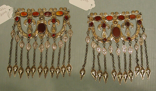 Dorsal Headdress Ornament, One of a Pair, Silver; with gilt applied decoration, connecting links with embossed decoration, ram’s-head terminals, loop-in-loop chains, and table-cut carnelians