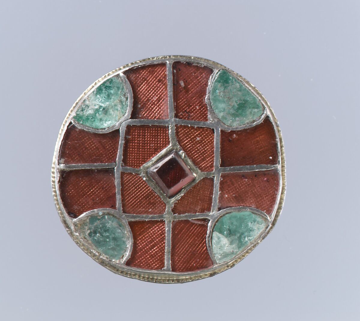 Disk Brooch, Silver-gilt cells, side strip, and beaded edging; garnets with deep-punched, "standard" foil backings; emerald; silver back with posts for spring and pin; no spring/pin extant, Frankish