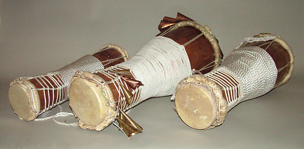 Batá, Brandon Rosser (American, active New York, late 20th century), Sweet maple, polyurethane finish, brass and copper bells, nylon, steel bolts, jet bead, deer skin heads, golden oak stain, red clay, American