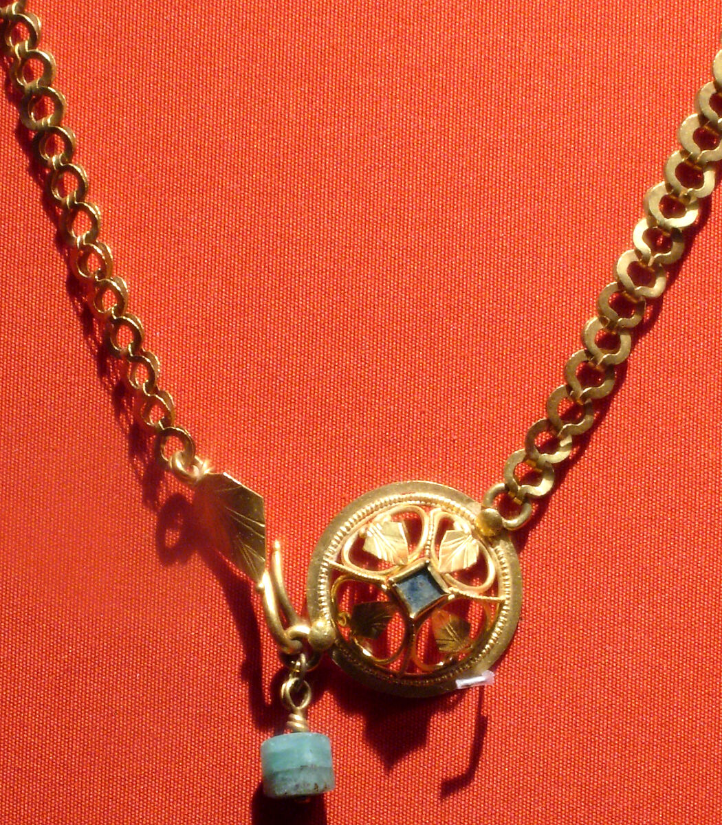 Chain terminating in a leaf motif, and having a raised openwork clasp ornament, gold, blue stone, emerald 
