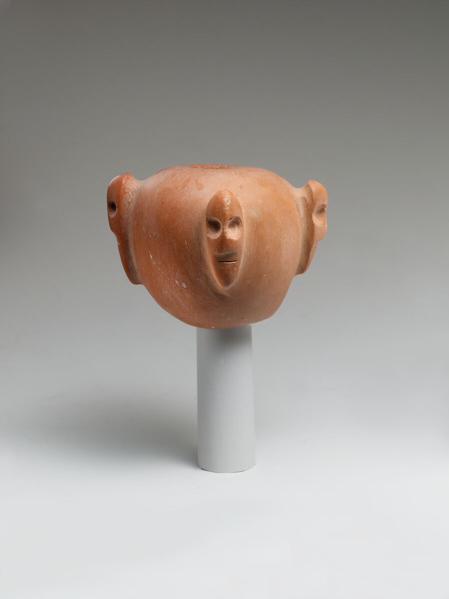 Piriform macehead with male faces, Limestone (pink), organic material