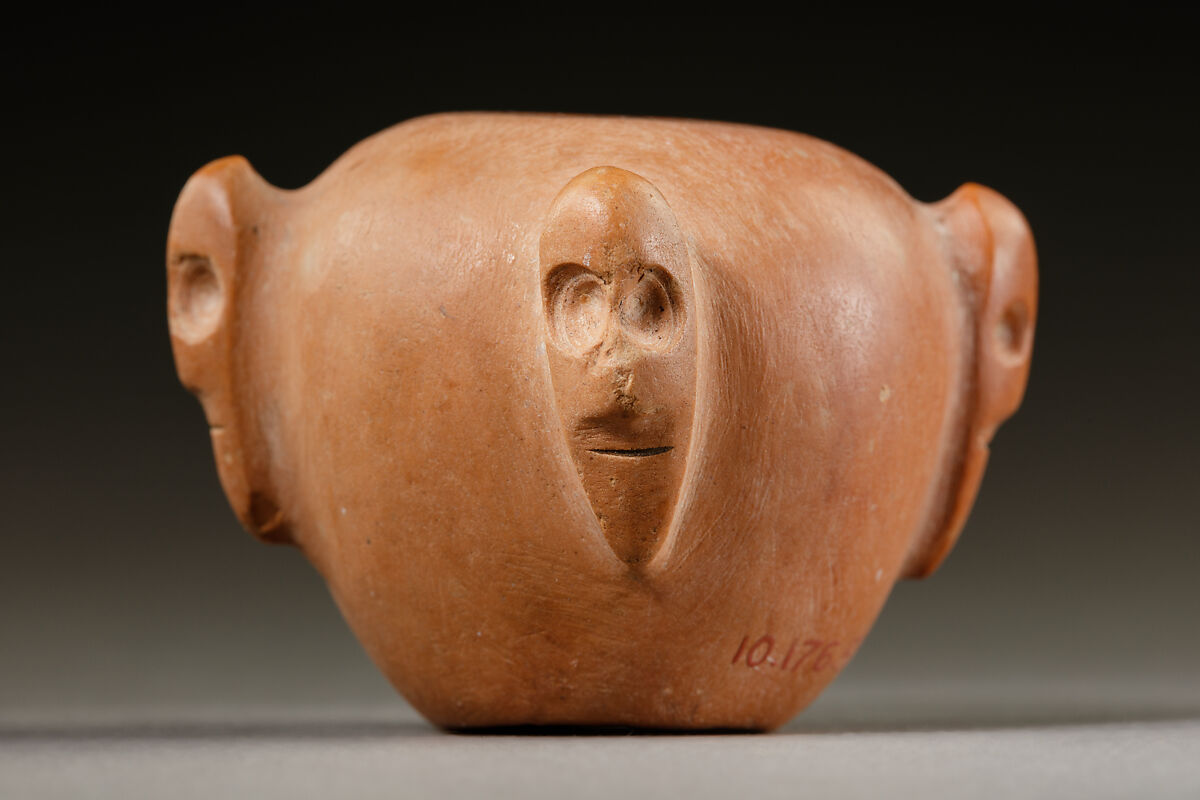 Piriform macehead with male faces, Limestone (pink), organic material