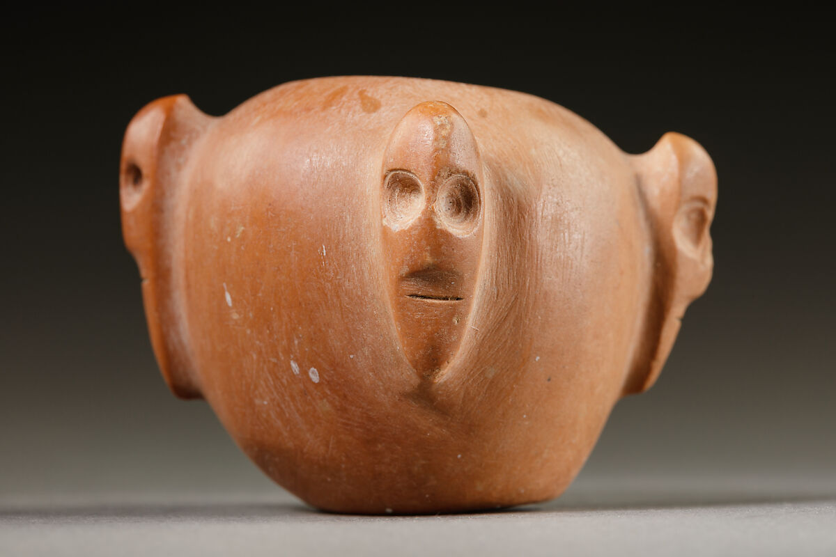 Piriform macehead with male faces, Limestone (pink), organic material